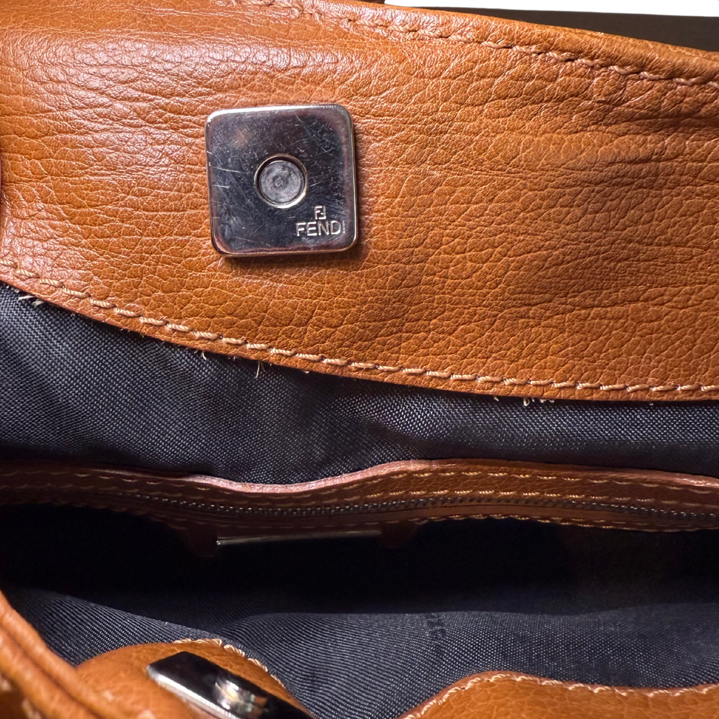 Close-up of a brown leather bag with a Fendi logo.