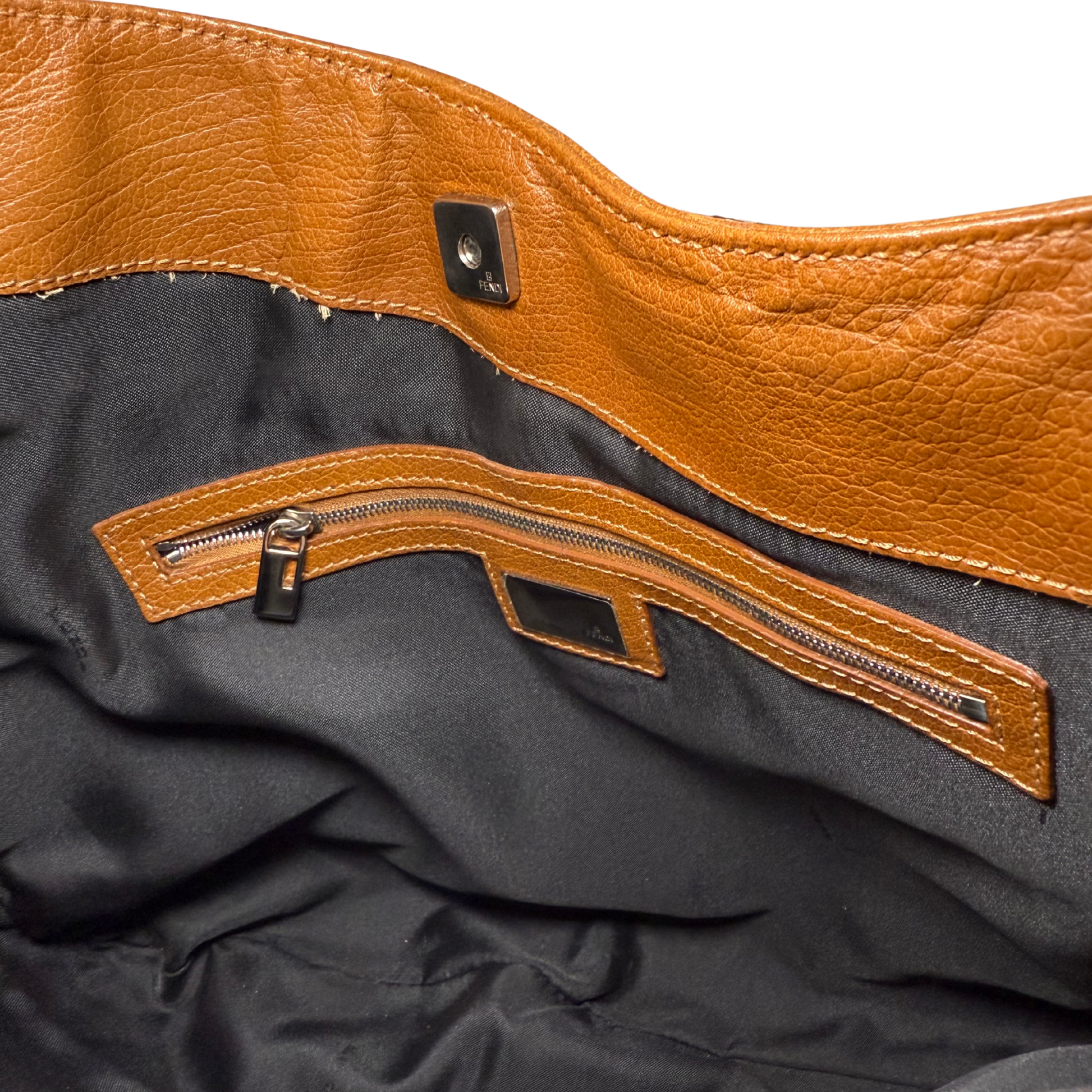 Close-up of a brown leather patch with zipper on a black fabric background