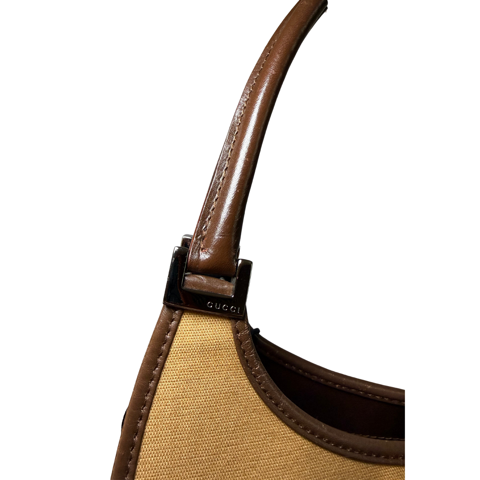Close-up of a brown handbag handle with visible Gucci logo.
