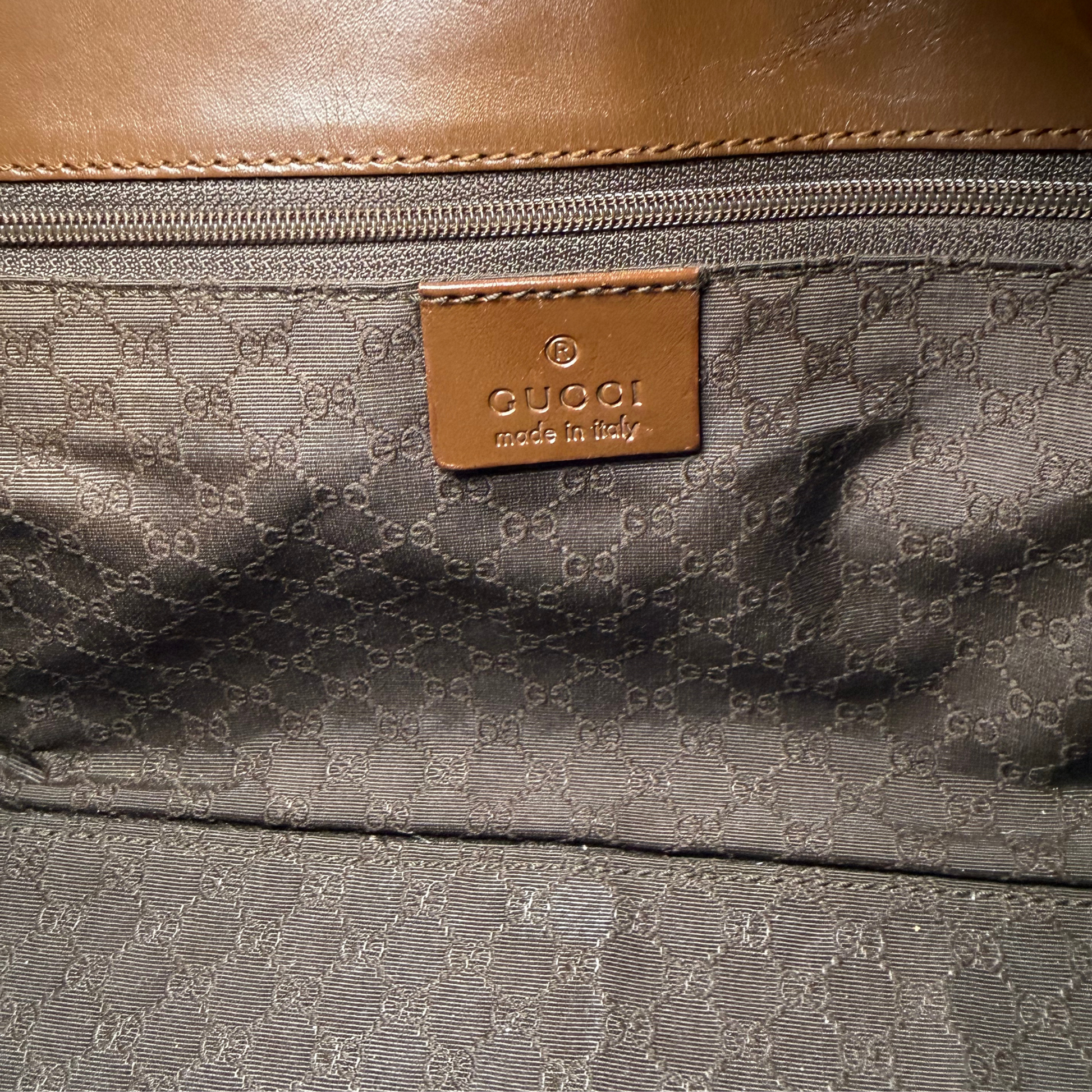 Close-up of a Gucci bag interior with a brown leather patch and monogram pattern.