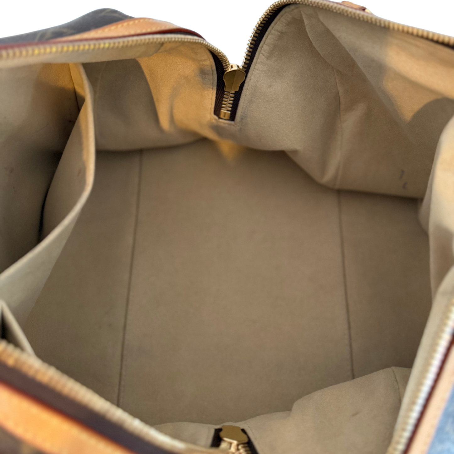 Close-up of a beige interior of a Louis Vuitton Bag with a gold zipper.