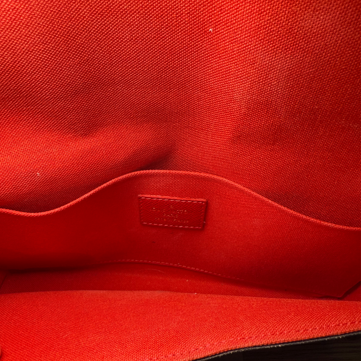 Close-up of a red fabric surface with a visible brand logo.