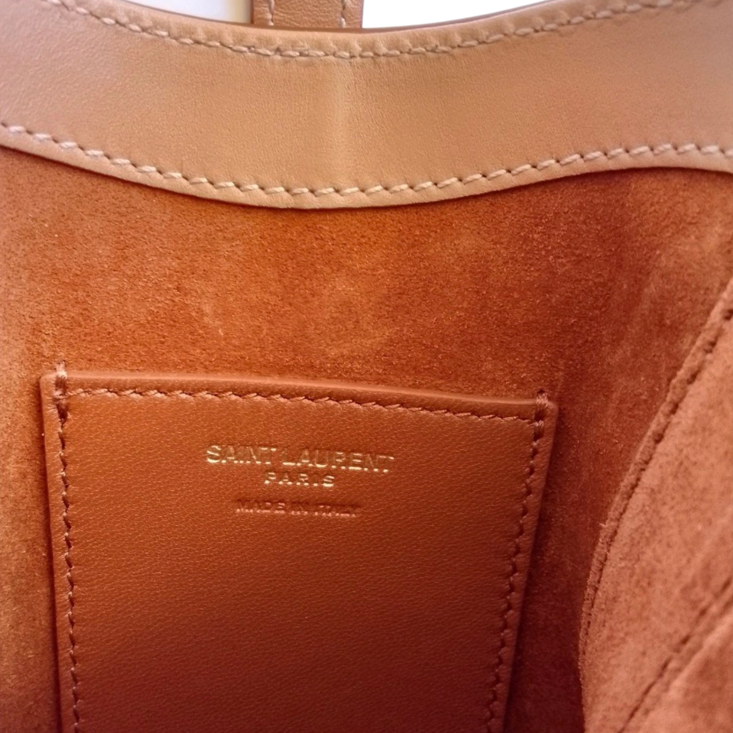 Close-up of a brown leather handbag with 'Saint Laurent Paris' branding.